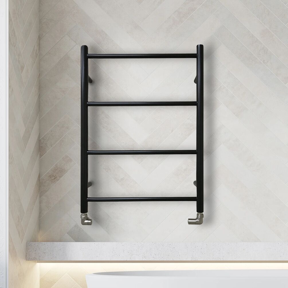 Lifestyle image of the The Sussex Range by JIS Rusper 700mm x 520mm Black Heated Towel Rail mounted on a white wall, behind a freestanding bathtub